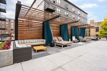 an outdoor patio with couches and chairs and a wooden canopy at Marquee, Minnesota